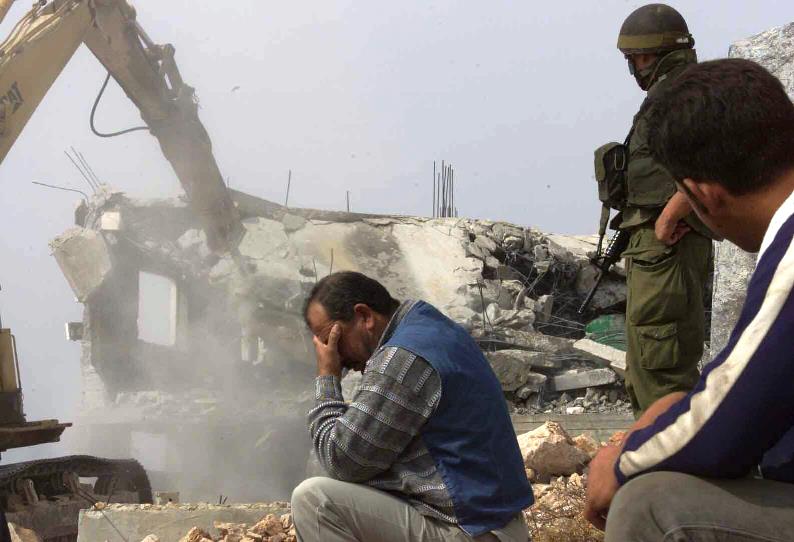 A Palestinian man can't look as his home is demolished by the Israel military.